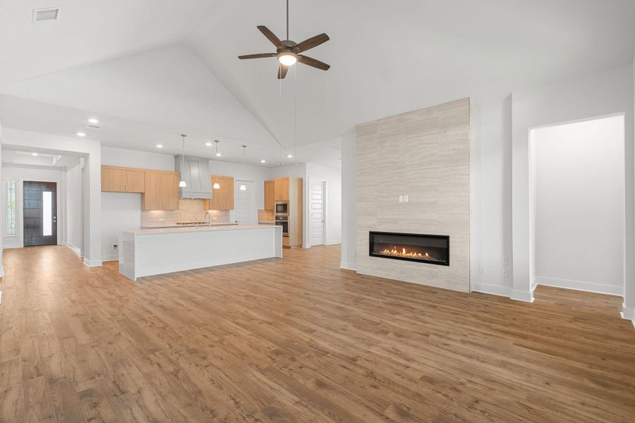 A spacious, open-concept living area with soaring vaulted ceilings and a sleek linear fireplace.