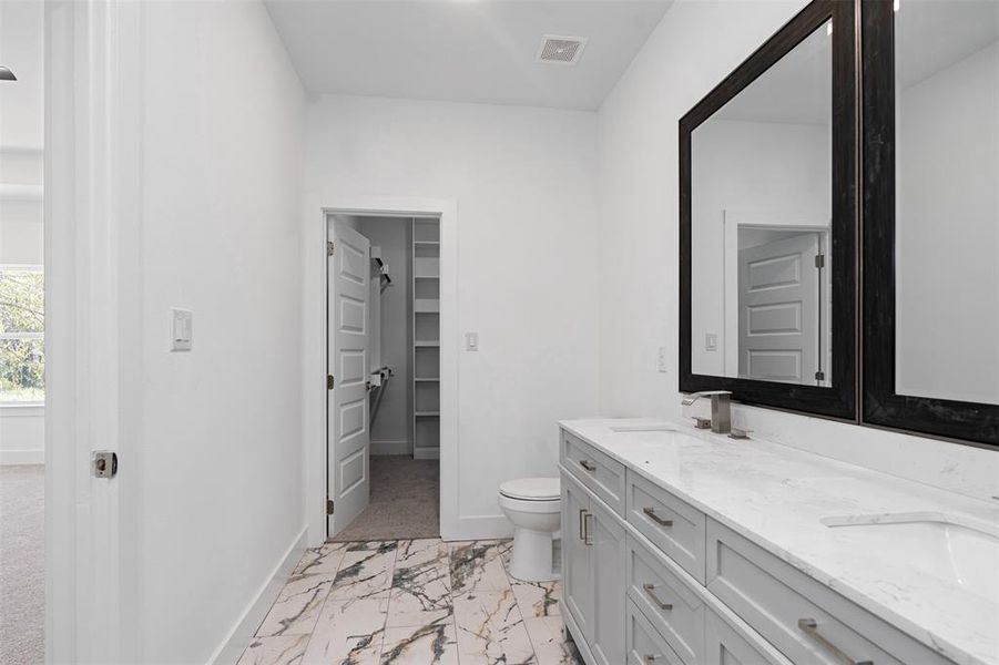 Bathroom featuring vanity and toilet and walk in closet