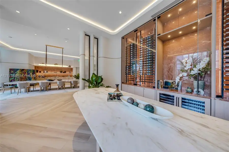 Custom wine storage with glass-front cabinetry, stone surfacing, wood-finish herringbone flooring, cove lighting, and recessed ceiling lights