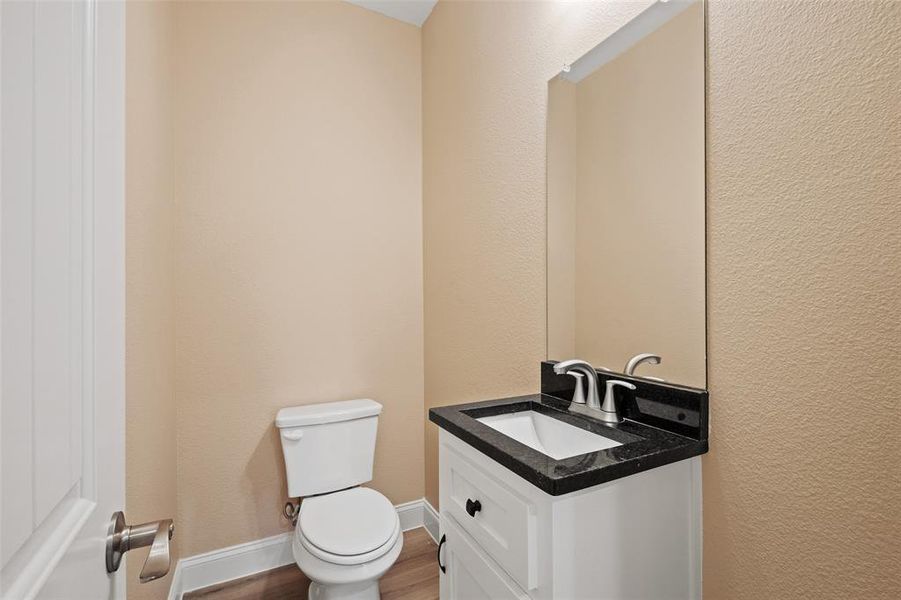 Powder room featuring a white single vanity with a black countertop, undermount sink, and brushed nickel fixtures Powder room featuring a white single vanity with a black countertop, undermount sink, and brushed nickel fixtures