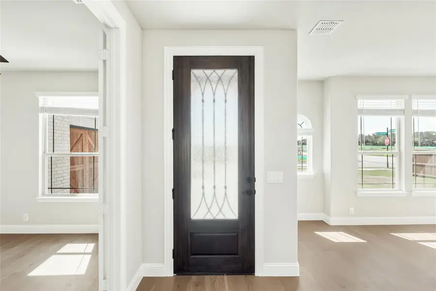 Home entryway with dark wood front door featuring decorative glass panel and light hardwood floors Home entryway with dark wood front door featuring decorative glass panel and light hardwood floors