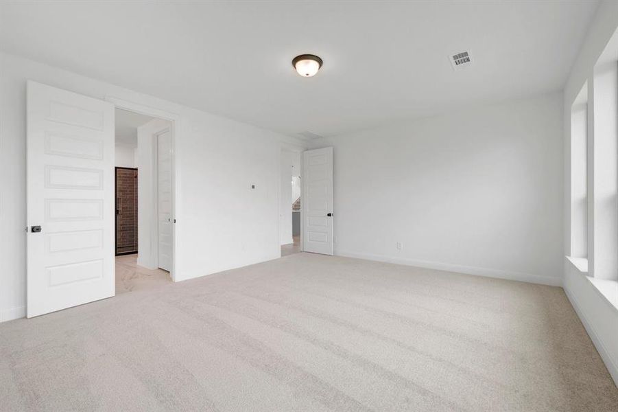 Spacious room featuring light-colored carpeting, white walls, and a ceiling-mounted light fixture
