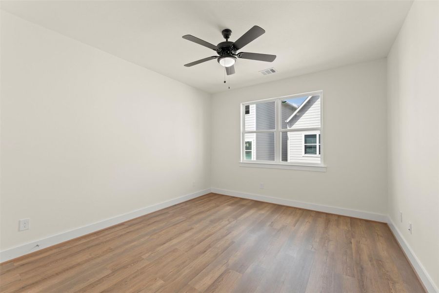 This room features fresh white walls, a ceiling fan, and a window offering natural light.
