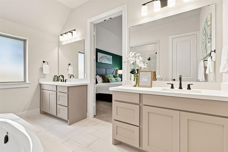 Separate dual vanities and a deep soaking tub create a luxurious primary bathroom retreat.