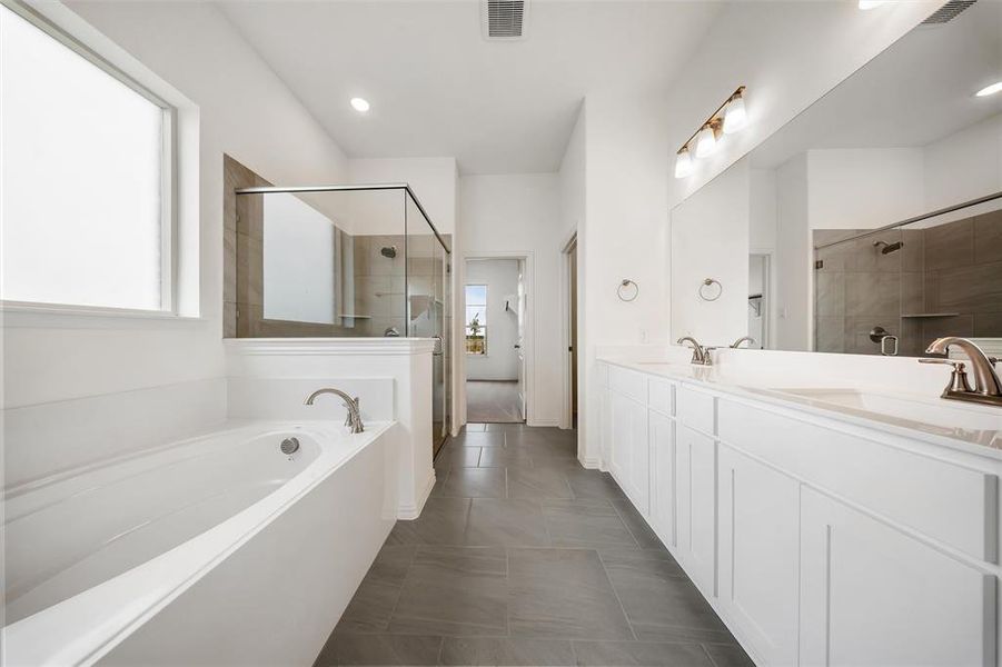 Bathroom featuring a shower stall, double vanity, a garden tub, dark tile patterned flooring, and recessed lighting Bathroom featuring a shower stall, double vanity, a garden tub, dark tile patterned flooring, and recessed lighting