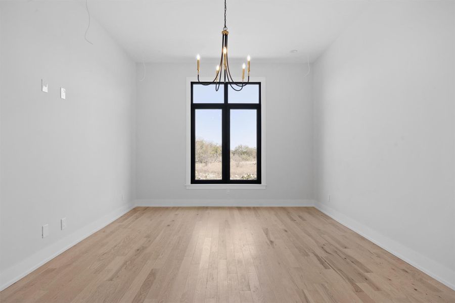 Guest room featuring baseboards, an inviting chandelier, and light wood finished floors