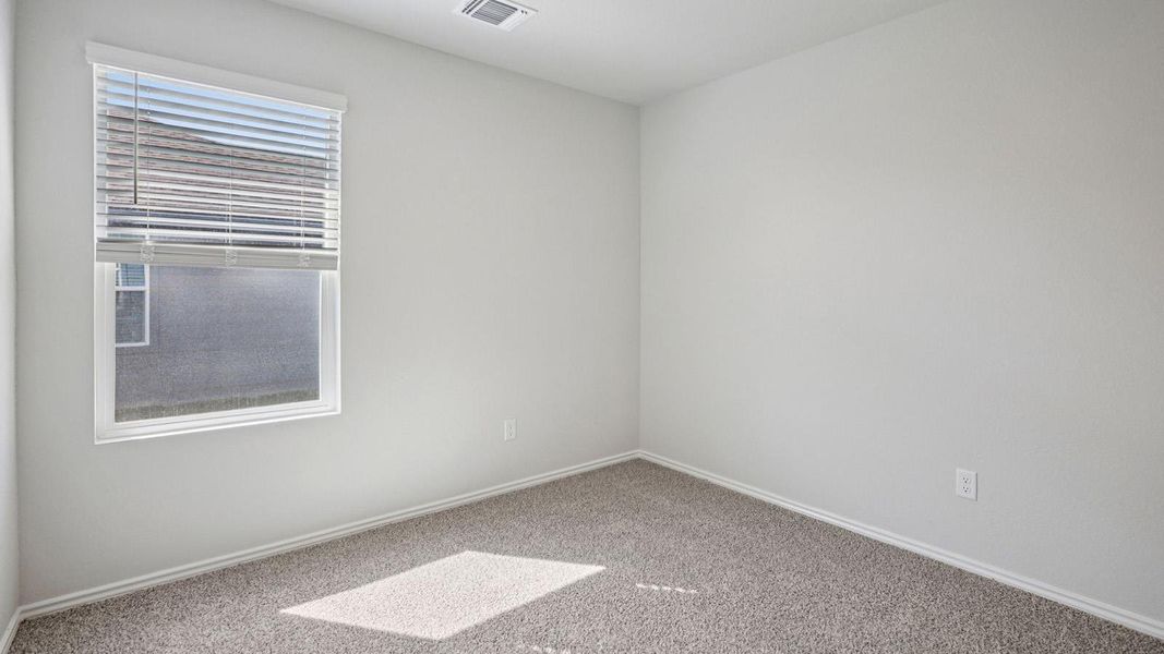 A well-lit bedroom offering a cozy ambiance with its soft, neutral-toned carpeting. A well-lit bedroom offering a cozy ambiance with its soft, neutral-toned carpeting.