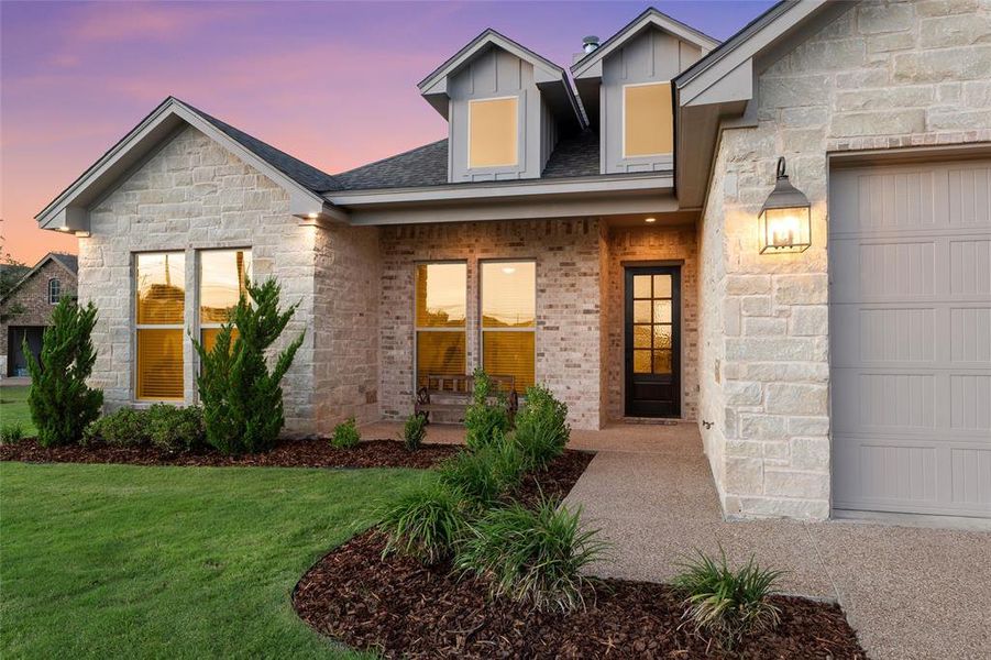 Stone and brick facade with covered front porch and glass-paneled front door. Stone and brick facade with covered front porch and glass-paneled front door.