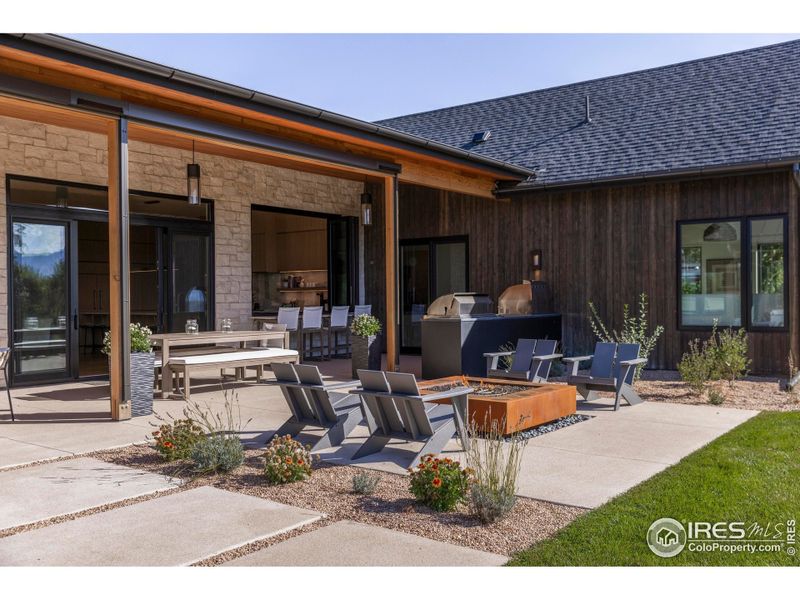 Designed for seamless outdoor living, the west patio showcases panoramic mountain scenery with multiple seating areas, a fire pit, and a fully equipped summer kitchen-complete with pizza oven, grill, and beverage fridge. Designed for seamless outdoor living, the west patio showcases panoramic mountain scenery with multiple seating areas, a fire pit, and a fully equipped summer kitchen-complete with pizza oven, grill, and beverage fridge.