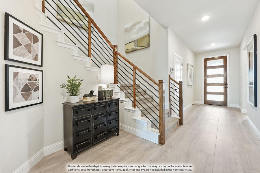 Entryway foyer with open staircase, wood railing, light hardwood floors, and glass-panel front door
