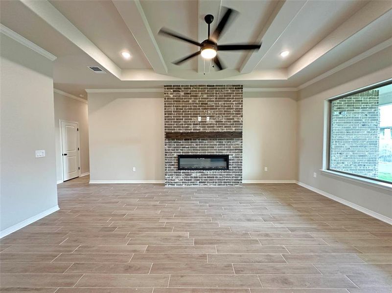 Unfurnished living room featuring ceiling fan, a fireplace, wood finish floors, recessed lighting, and crown molding