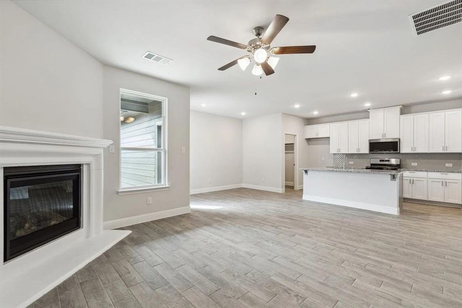 Unfurnished living room with light wood-type flooring and ceiling fan