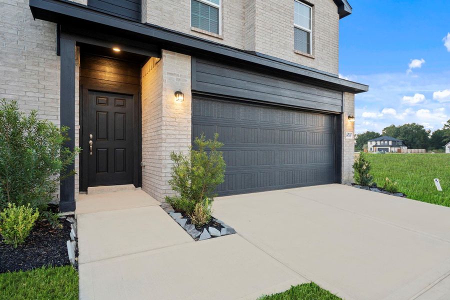 The inviting front entry features a covered porch and elegant doorway framed by clean brick lines. Thoughtfully designed landscaping adds a touch of greenery, creating a warm and welcoming atmosphere right at your doorstep. This is an energy saving home to help you save money!  Stop paying the Landlord their investment and start investing in you!  Start your memories today and make that call!