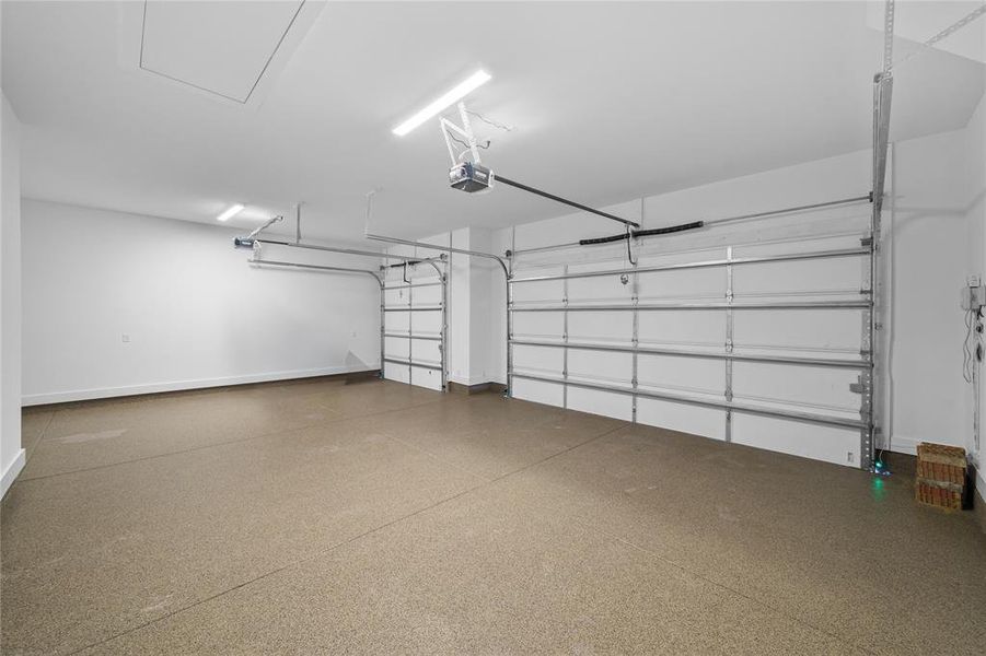 Two-car garage featuring a speckled epoxy floor coating and two metal sectional garage doors