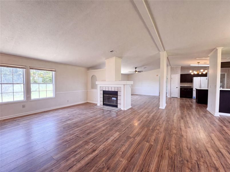 A double-sided fireplace anchors the expansive open living area featuring classic wood-look flooring.