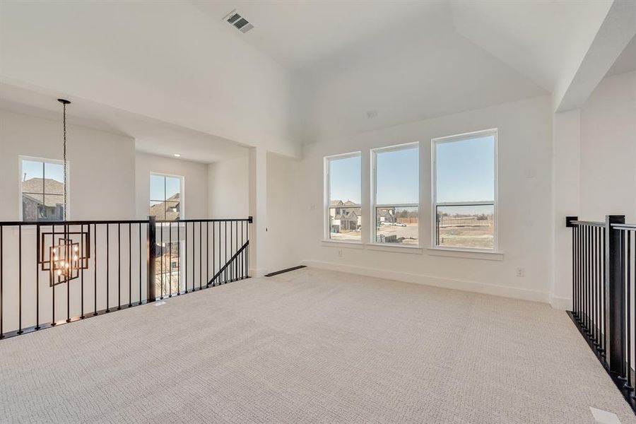 Carpeted empty room with baseboards and lofted ceiling Carpeted empty room with baseboards and lofted ceiling