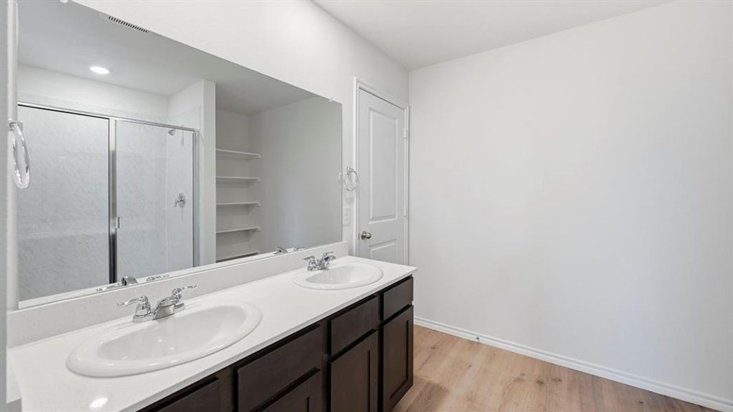 Bathroom featuring light wood finished floors, a shower stall, and double vanity Bathroom featuring light wood finished floors, a shower stall, and double vanity