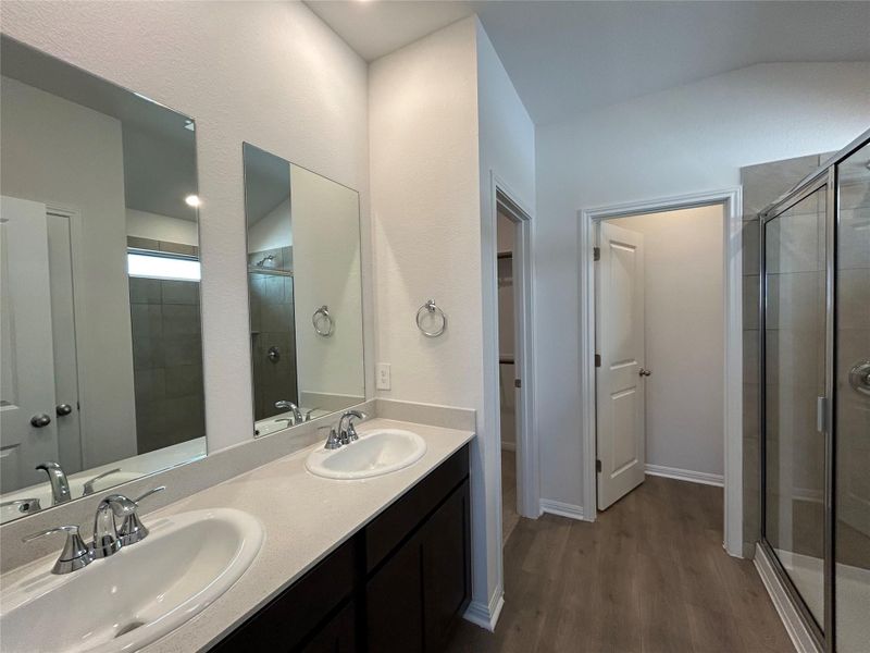 Full bathroom with a shower stall, double vanity, dark wood-type flooring, and a closet Full bathroom with a shower stall, double vanity, dark wood-type flooring, and a closet