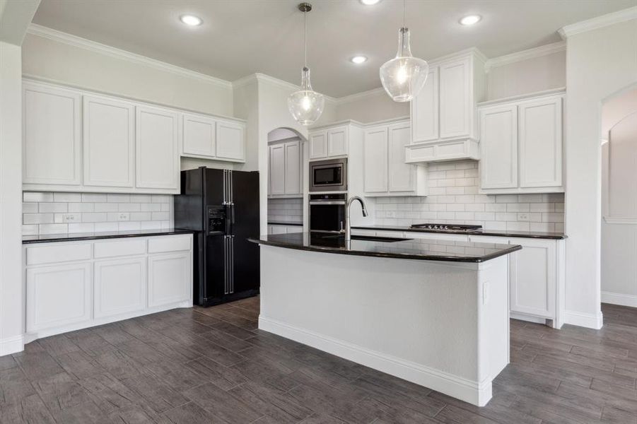 Kitchen featuring appliances with stainless steel finishes, decorative light fixtures, white cabinets, gorgeous ebony granite countertops & beautiful subway tile.  The Frig will stay with the property.