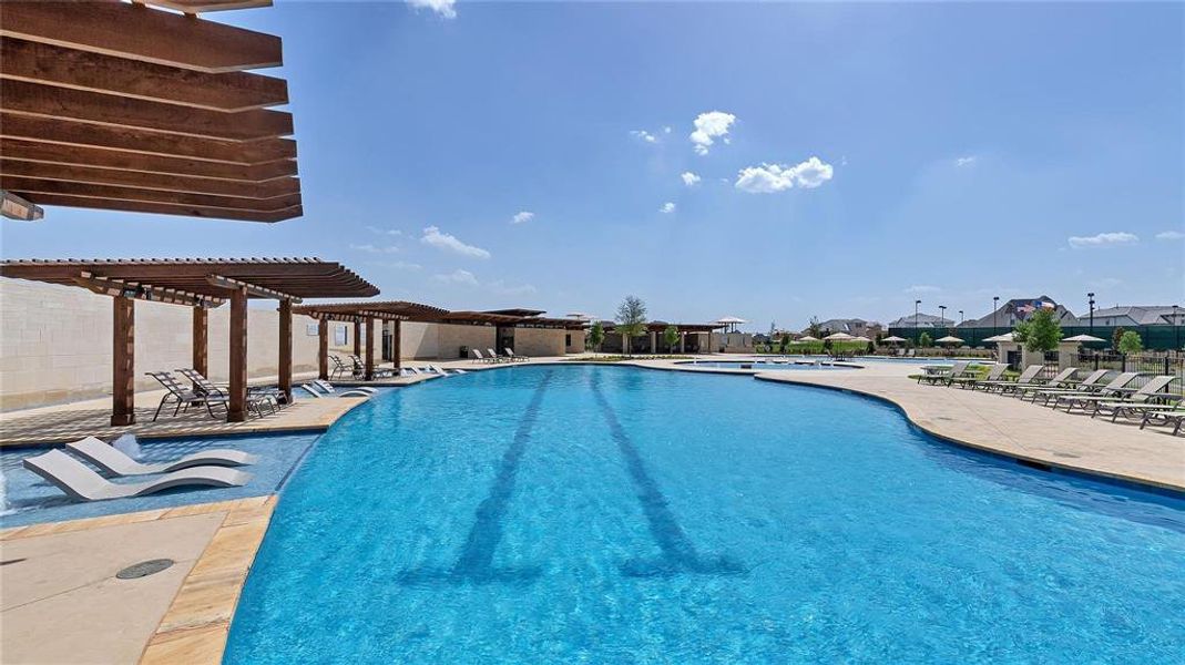 Expansive resort-style swimming pool featuring multiple lap lanes, a shallow tanning ledge with in-pool loungers, and surrounding pergolas with lounge seating