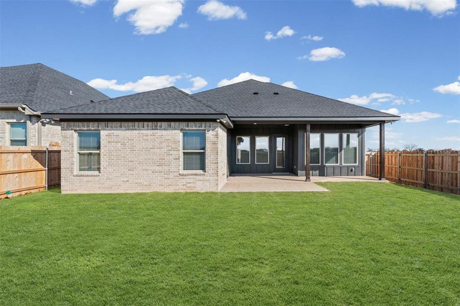 Rear view of property featuring a shingled roof, a patio, a fenced backyard, and brick siding