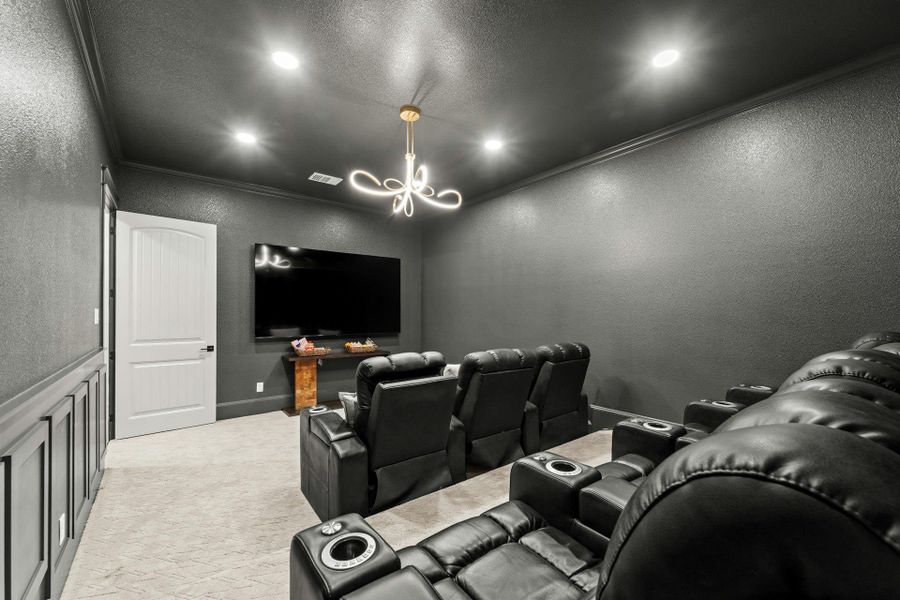 Dedicated entertainment room featuring dark-painted walls, light-colored carpet flooring, recessed ceiling lighting, a contemporary chandelier, and wainscoting detail