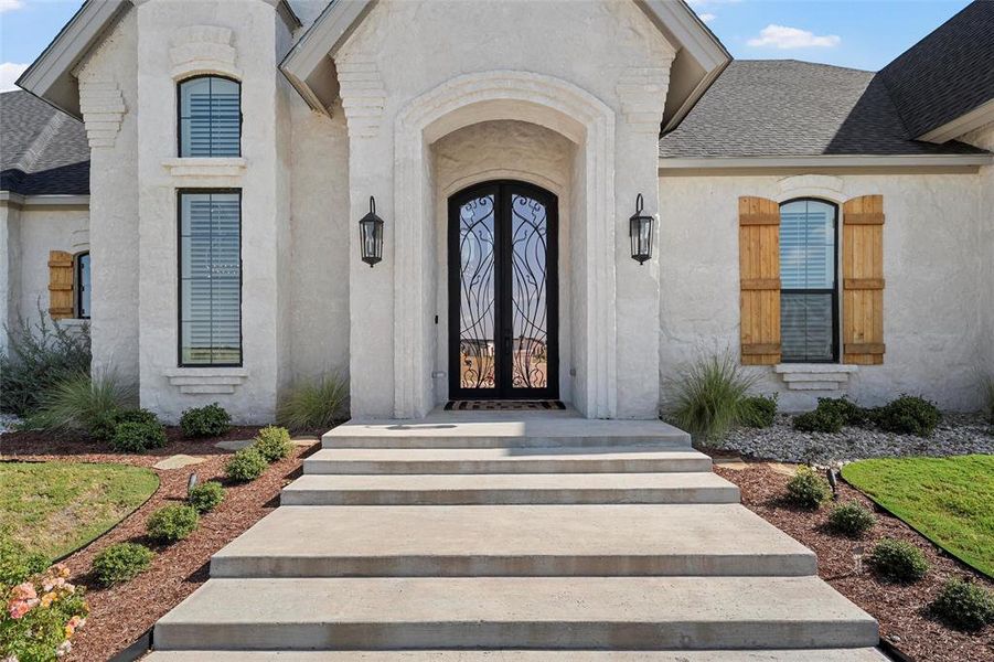 View of exterior entry with french doors, a shingled roof, and stucco siding