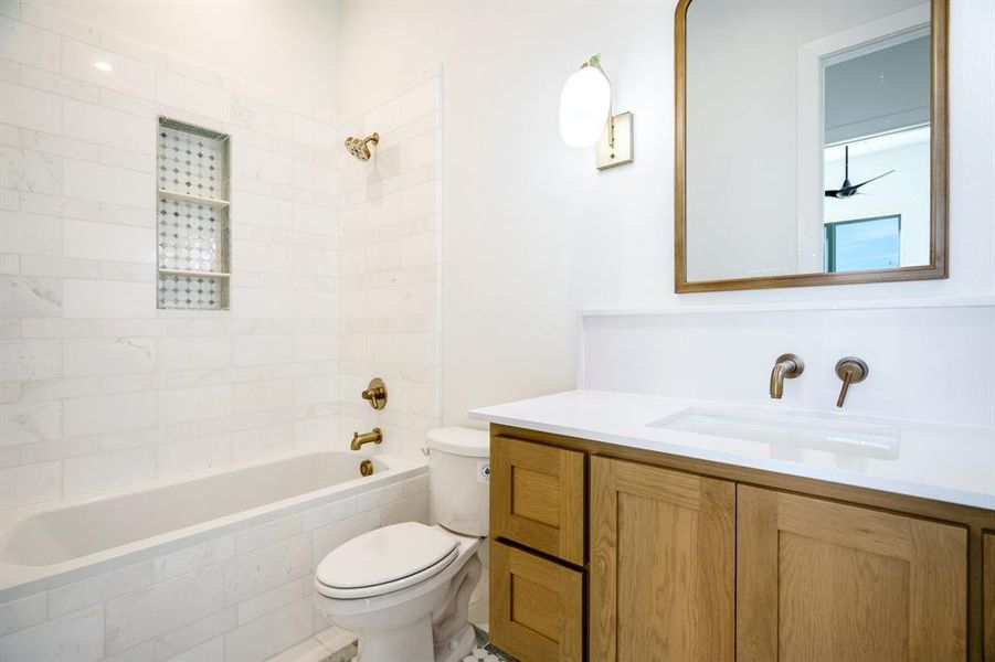 Full bathroom featuring vanity, tiled shower / bath combo, and toilet