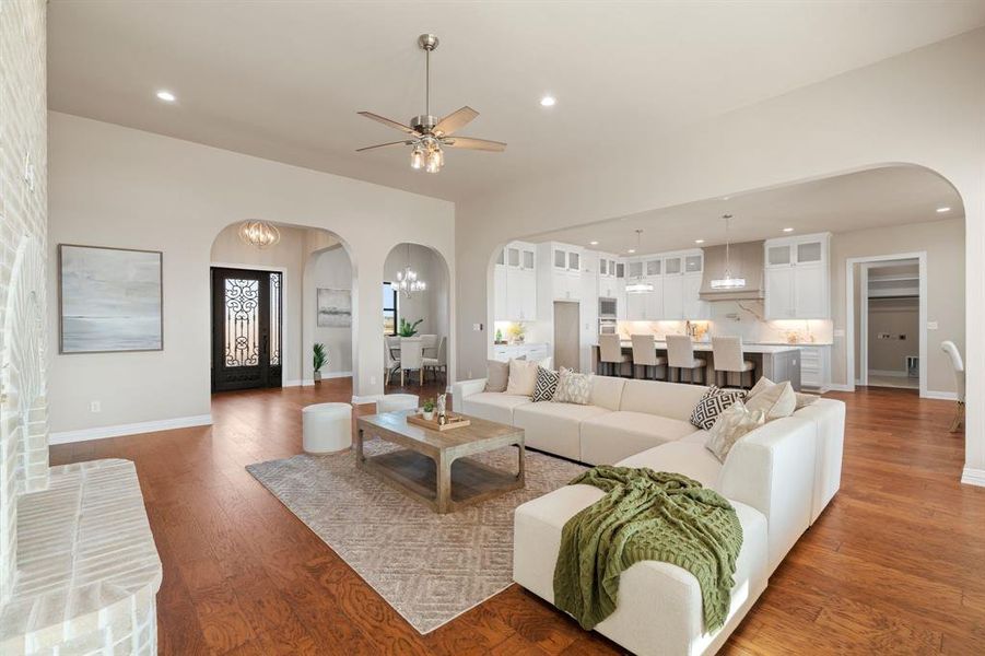 Living room with dark wood-type flooring and ceiling fan with notable chandelier