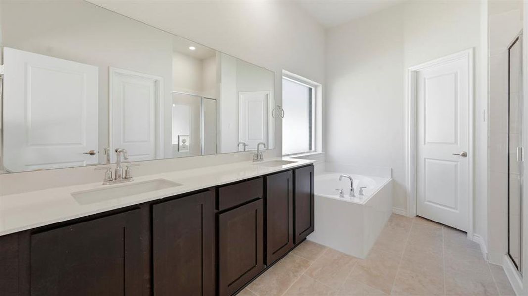 Full bath featuring a stall shower, double vanity, a bath, and light tile patterned floors Full bath featuring a stall shower, double vanity, a bath, and light tile patterned floors