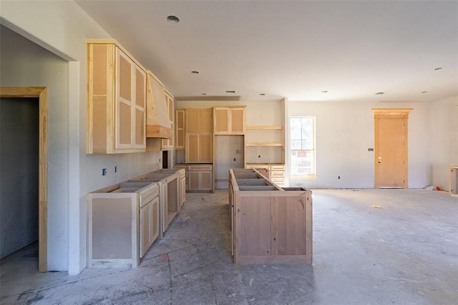 Kitchen with a center island, light brown cabinets, and premium range hood