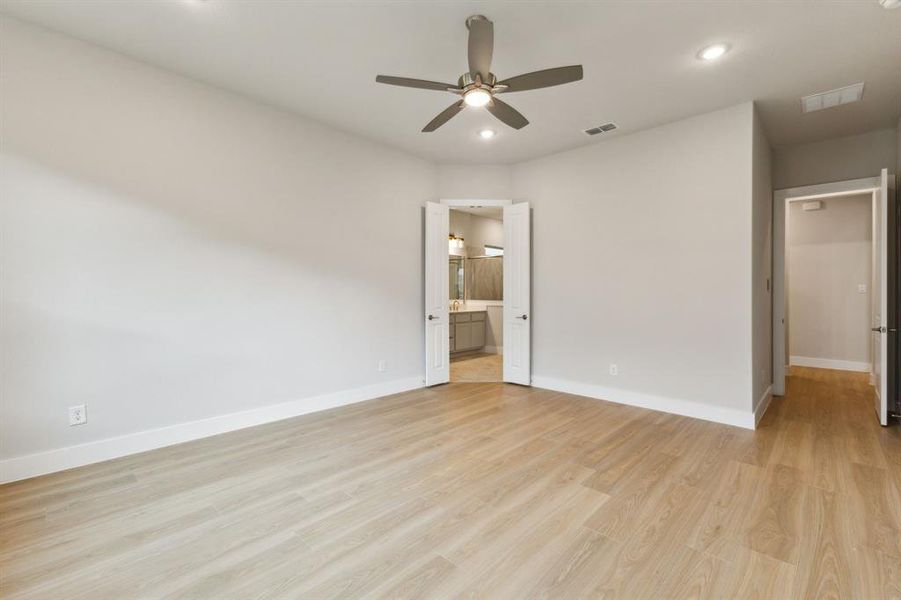 Unfurnished bedroom featuring light wood finished floors, recessed lighting, ensuite bathroom, and ceiling fan