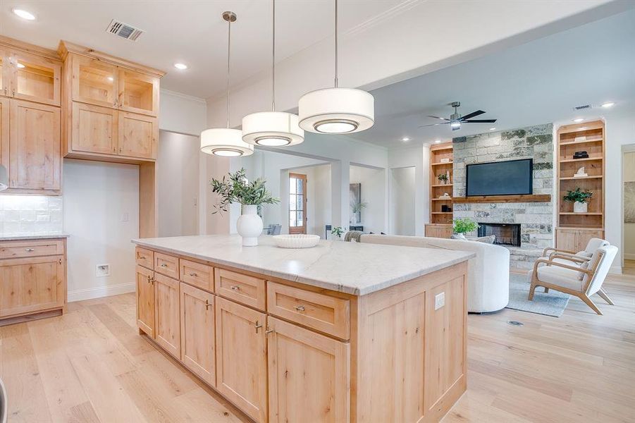 Kitchen with custom Knotty Alder wood cabinets to the ceiling, leathered Quartzite counters, tile backsplash, decorative lighting, ample storage, soft close doors and drawers, and gas cooktop.