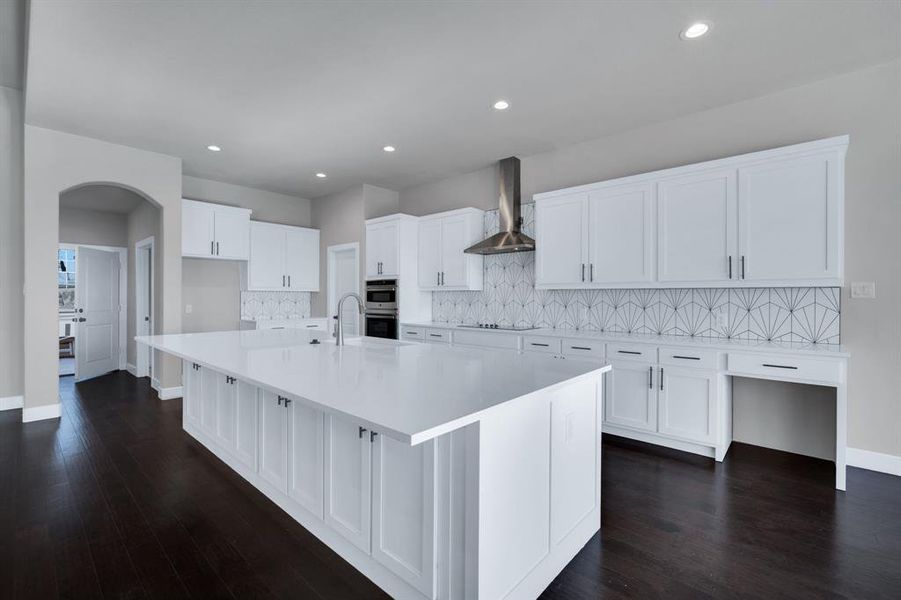 Kitchen with an island with sink, decorative backsplash, dark hardwood / wood-style floors, and wall chimney exhaust hood