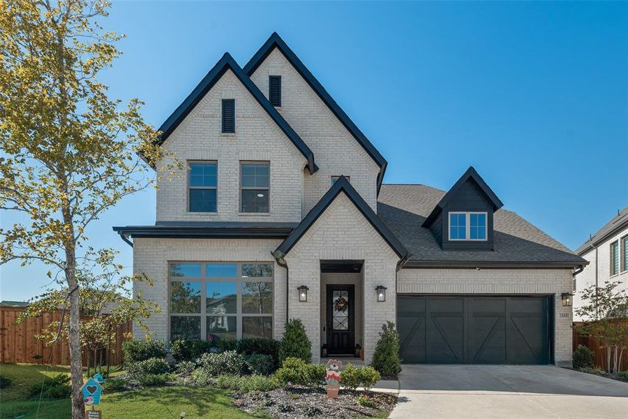 View of front of home featuring brick siding, driveway, and a shingled roof