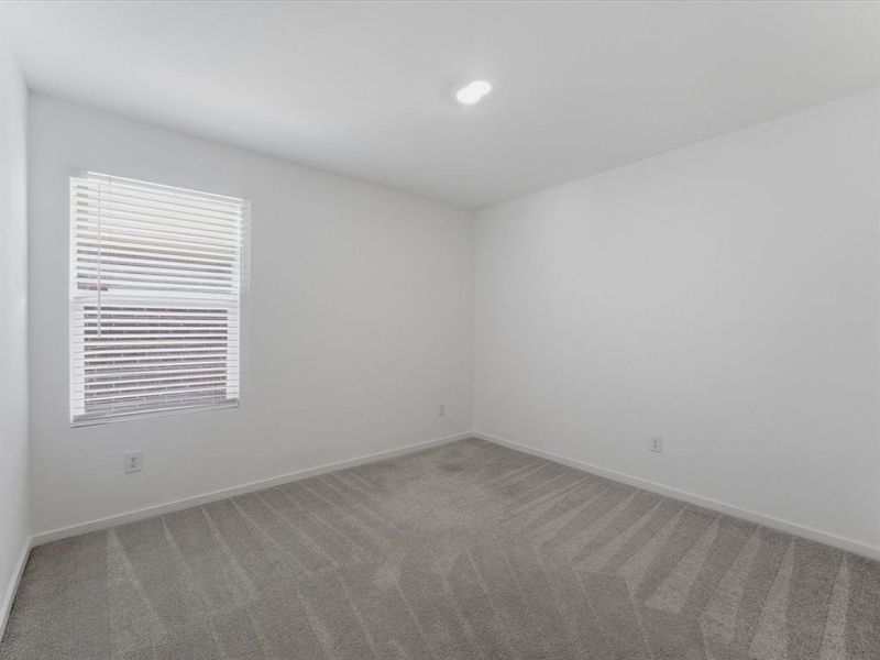 Room featuring light gray patterned carpeting, white walls, a single window with blinds, and an overhead lighting fixture