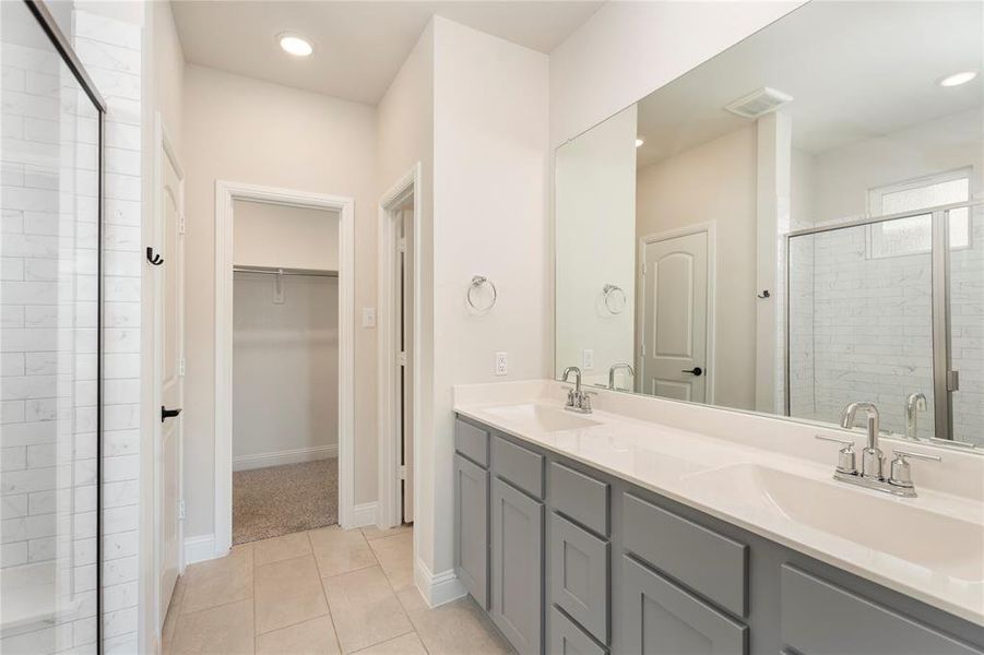 Bathroom featuring a shower stall, double vanity, a walk in closet, tile patterned flooring, and recessed lighting