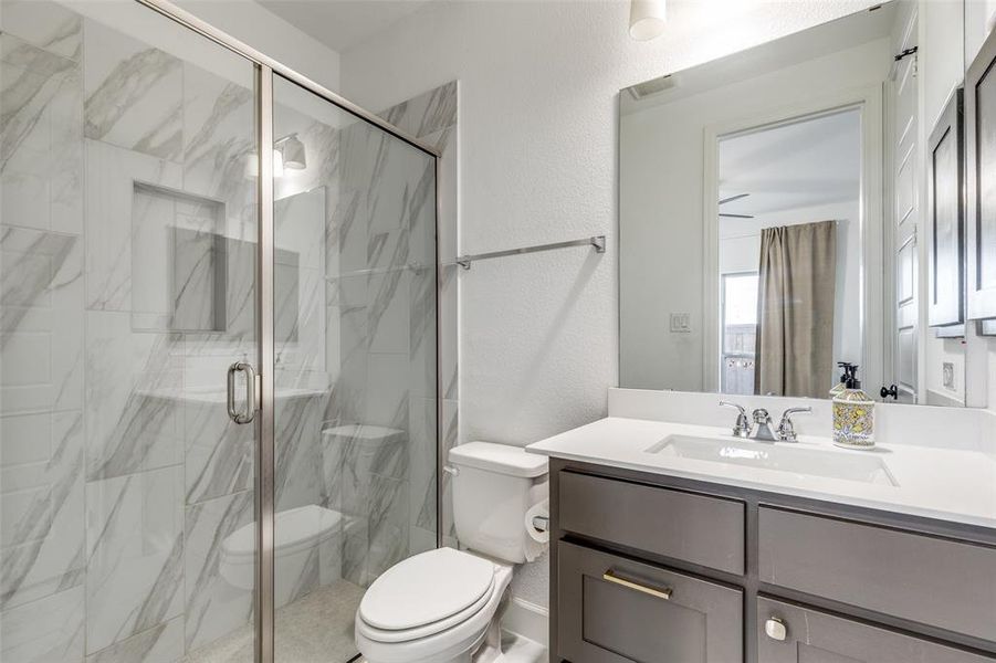 Bathroom featuring a textured wall, vanity, and a marble finish shower
