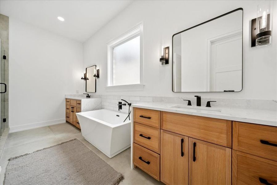 Bathroom featuring tile patterned flooring, shower with separate bathtub, and vanity