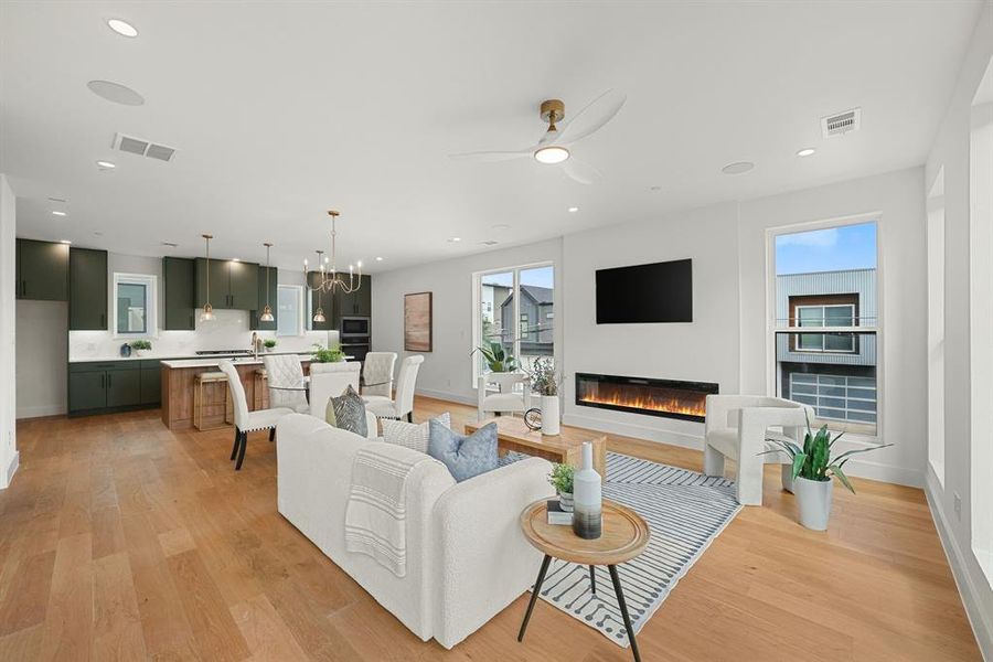 Open-concept interior featuring wood-finish flooring, recessed lighting, and a linear electric fireplace Open-concept interior featuring wood-finish flooring, recessed lighting, and a linear electric fireplace
