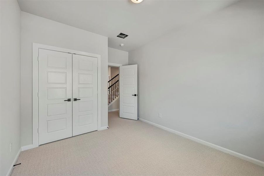 Unfurnished bedroom with light colored carpet and a closet Unfurnished bedroom with light colored carpet and a closet