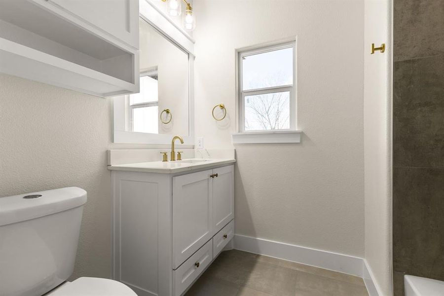 Bathroom with toilet, tile patterned floors, baseboards, and vanity