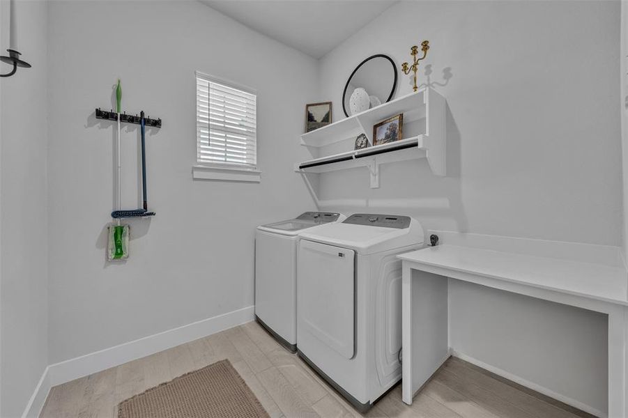 Dedicated utility area featuring wood-finish flooring, a window with blinds, built-in shelving, and a built-in countertop