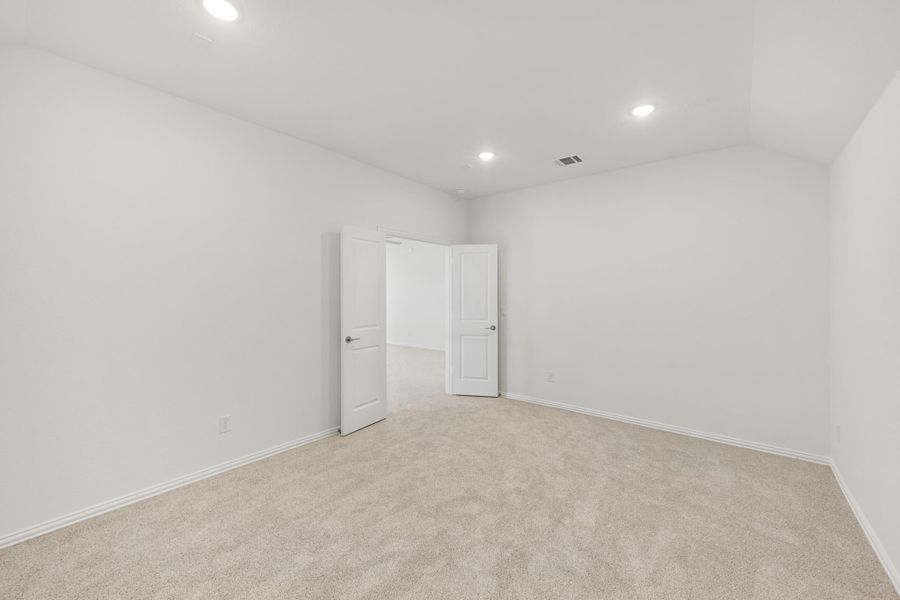 Empty bedroom with beige carpet, white walls, recessed lighting, and open closet door