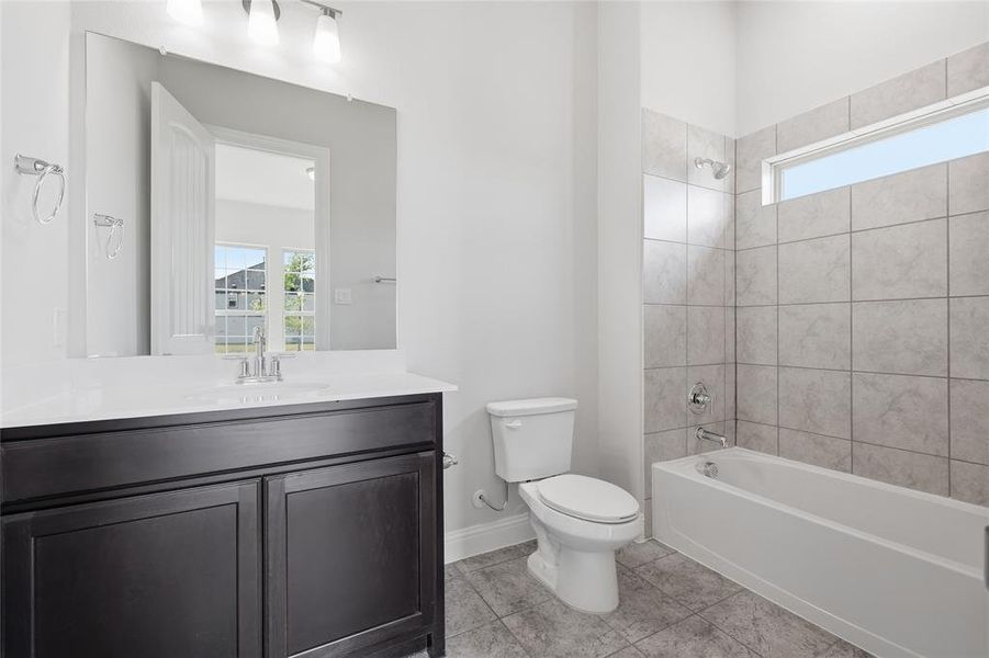 Bathroom featuring healthy amount of natural light, vanity, shower / tub combination, and light tile patterned floors Bathroom featuring healthy amount of natural light, vanity, shower / tub combination, and light tile patterned floors