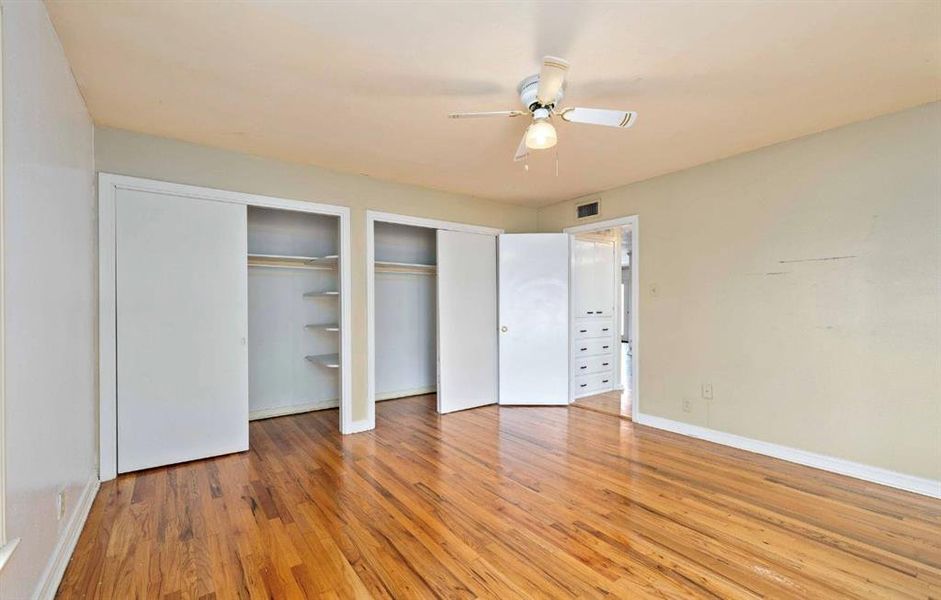 Unfurnished bedroom with two closets, light wood finished floors, and ceiling fan