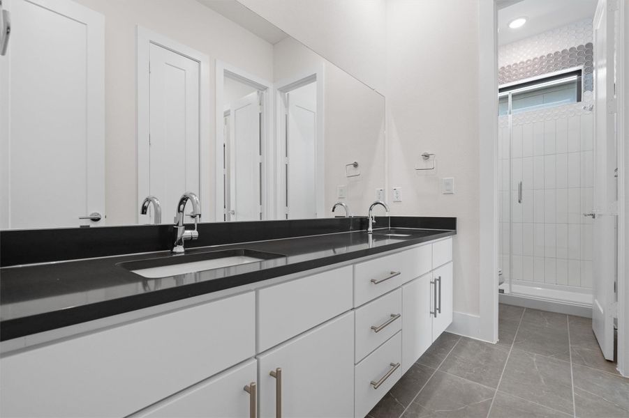 Full bath with double vanity, a stall shower, and dark tile patterned flooring Full bath with double vanity, a stall shower, and dark tile patterned flooring