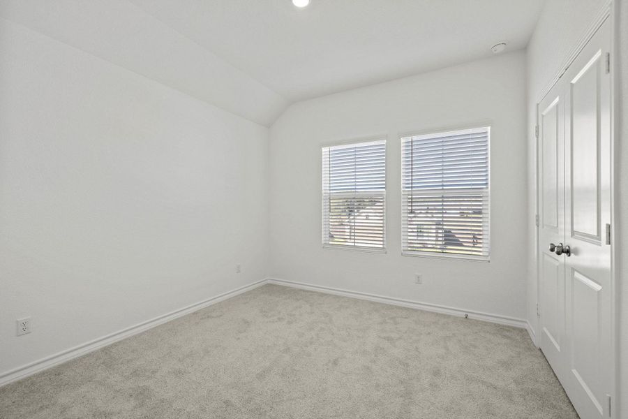 Unfurnished bedroom with light colored carpet, a closet, and vaulted ceiling
