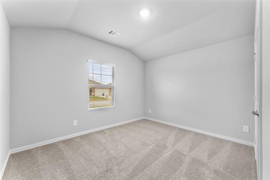Unfurnished room featuring vaulted ceiling and carpet flooring Unfurnished room featuring vaulted ceiling and carpet flooring