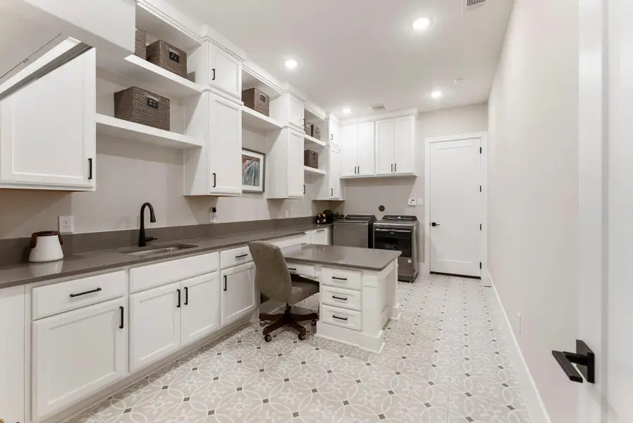 The utility room was expanded and customized to offer far more function than a standard laundry space. Built-in cabinetry, hanging space, and a lowered work area support laundry, storage, sewing, wrapping, and household organization.